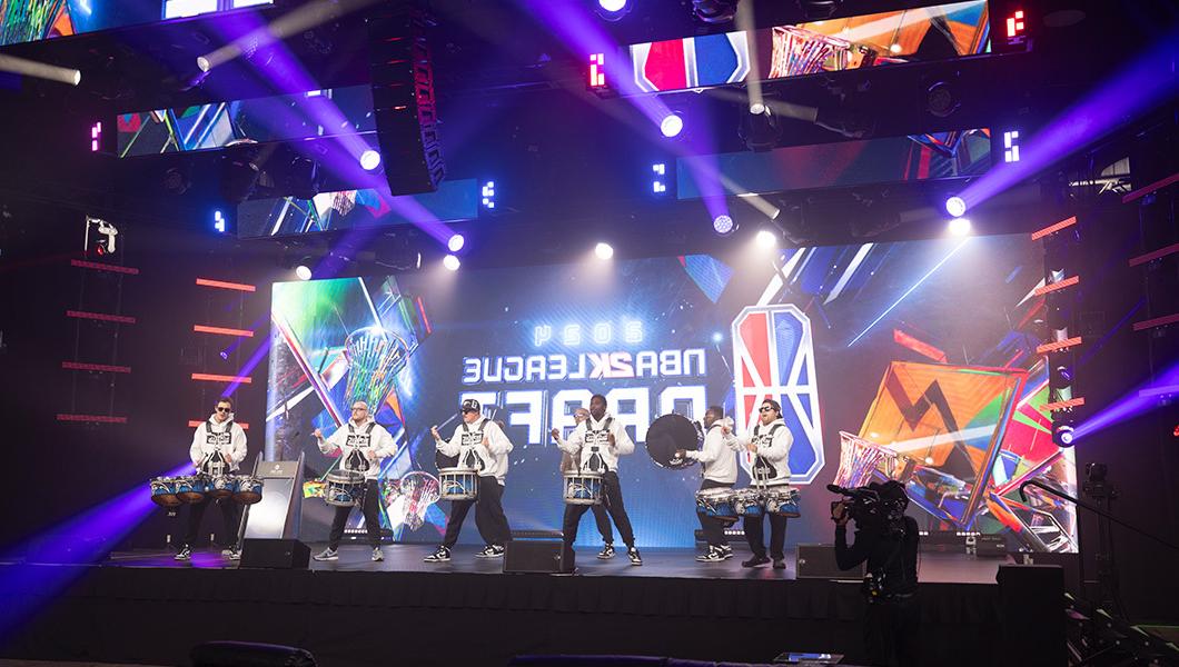 舞台上的一个大LED屏幕上写着“NBA 2 k联赛选秀”，鼓线正在表演.”
